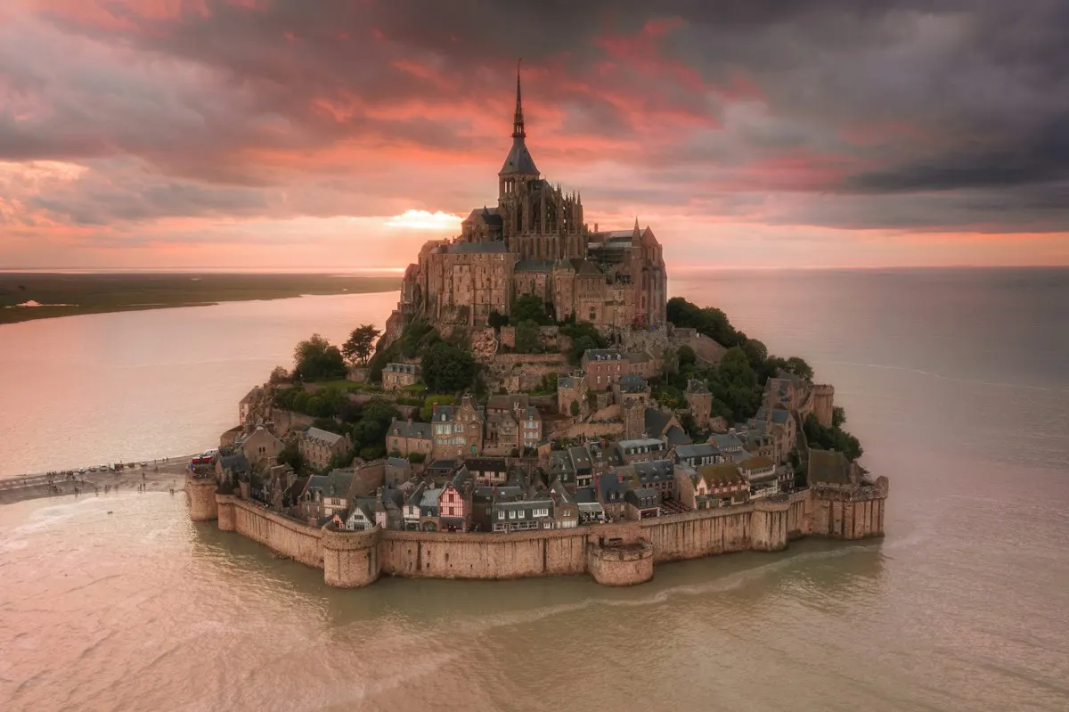 Abbaye et village du Mont-Saint-Michel entourés par la baie au coucher du soleil